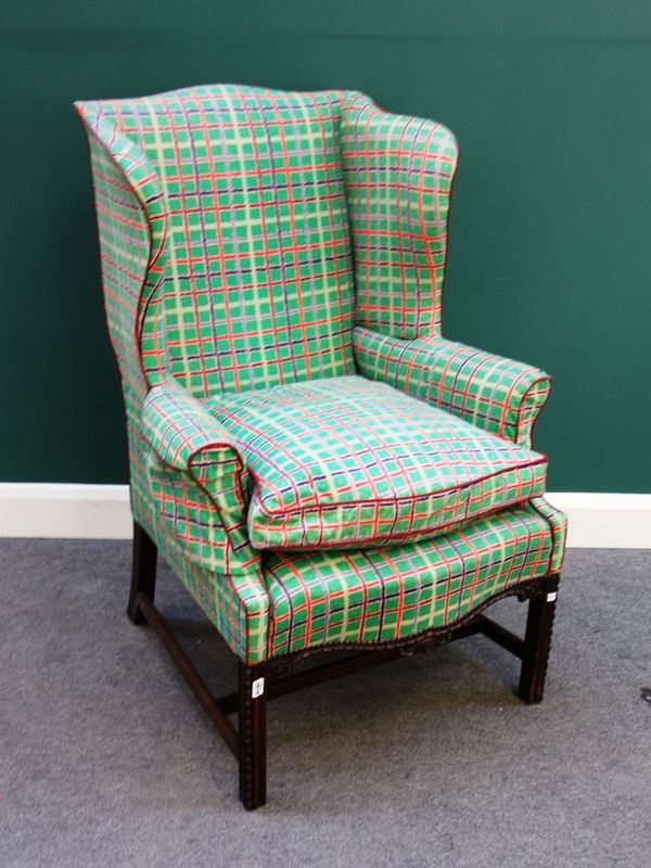 An 18th century style wing back armchair, with serpentine seat on carved mahogany square supports.