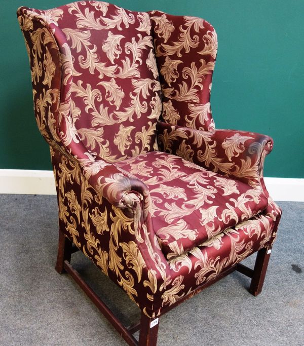 A 19th century wingback armchair of 18th century design, on mahogany block supports.