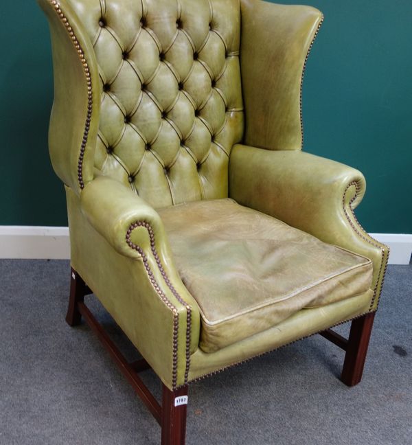 A George II style brass studded green leather upholstered wing back armchair, on channelled square supports.