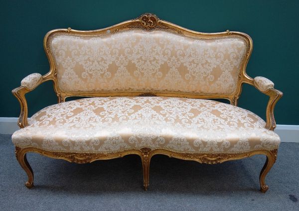 A Louis XV style gilt framed sofa, with carved and shaped back over open arms and double serpentine seat, on scroll supports, 150cm wide.