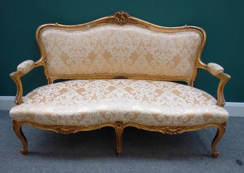 A Louis XV style gilt framed sofa, with carved and shaped back over open arms and double serpentine seat, on scroll supports, 150cm wide.