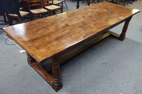 A 17th century style yew refectory table, the cleated plank top on four turned supports united by H stretcher, 98cm wide x 275cm long.