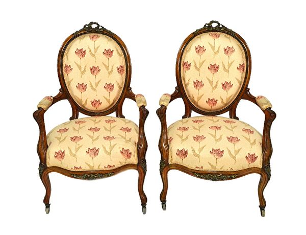 A pair of mid 19th century gilt metal mounted walnut armchairs, with ribbon tied crest over open arms and serpentine seat on scroll supports.   257  I