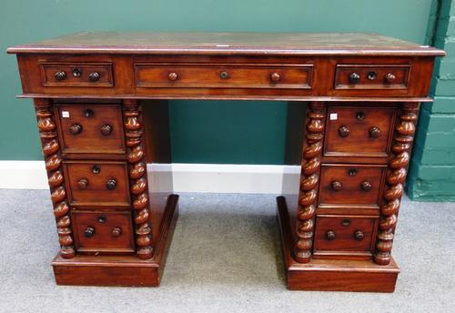 A small Victorian mahogany pedestal desk, with nine drawers flanked by split barleytwist supports, on plinth base, 115cm wide.