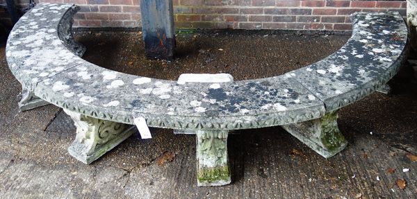 A large composite stone half circular garden bench, the three piece top and seven scroll supports, 322cm wide.