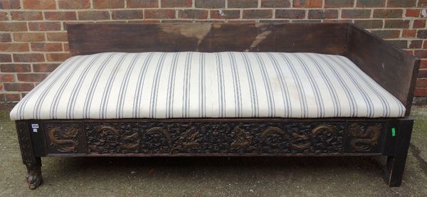 An opium bed, constructed from 19th century and later elements, with carved Chinese parcel gilt hardwood panels, on hairy paw feet, 195cm wide x 90cm