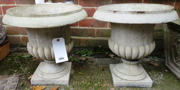 A pair of composition stone campana urns on turned socles, 40cm high, together with a pair of tapering square planters, relief moulded with Prince of