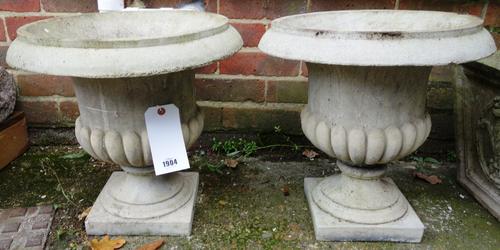A pair of composition stone campana urns on turned socles, 40cm high, together with a pair of tapering square planters, relief moulded with Prince of