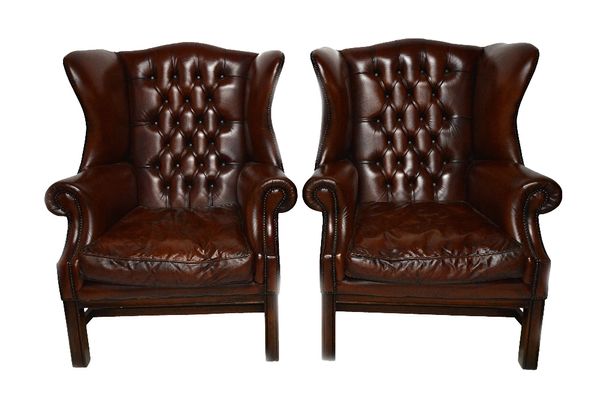 A large pair of early 18th century style studded brown leather upholstered wing back armchairs, on block supports (2).  Illustrated