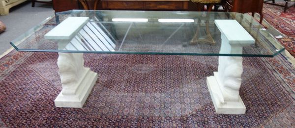 A 20th century dining table, the canted rectangular glass top on a pair of carved marble shell trestle end standards, 113cm wide x 212cm long.