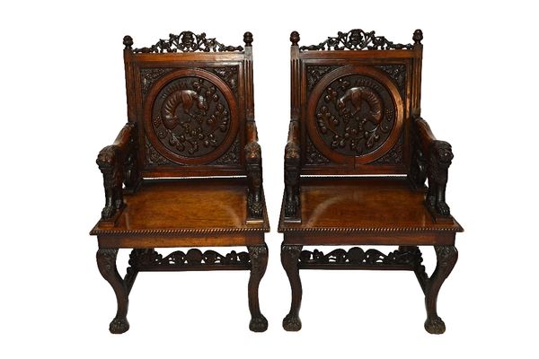 A pair of Anglo Indian teak armchairs, circa 1900, each with relief carved backs depicting mythological beats over open arms terminating in stylised t