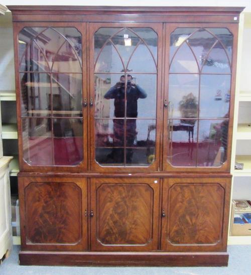 A William IV mahogany bookcase cupboard the three Gothic arch astragal glazed doors over three cupboards on plinth base, 182cm wide x 215cm wide.
