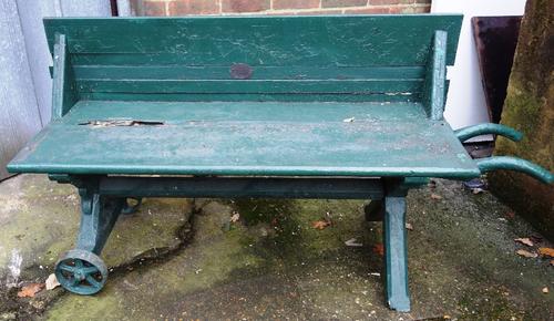 A 19th century green painted portable metamorphic garden bench with a pair of cast iron wheels and barrow type handles, bearing plaque 'Queen Victoria
