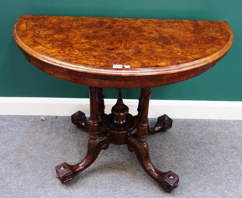 A Victorian inlaid figured walnut card table, the semi elliptic top on four turned columns and downswept supports, 107cm wide.