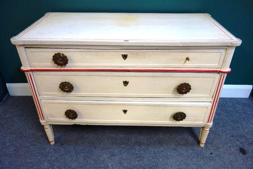 A 19th century (later decorated) cream three drawer commode in the Louis XVI style, with red detailing on turned legs, 125cm wide.Provenance- from the