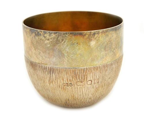 A silver tumbler cup, with partly bark textured decoration beneath a wide plain band, by Gerald Benney, London 1975, weight 109 gms, with a hinged cas