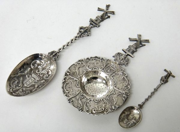 A Dutch tea strainer, with a decorated border and with a windmill finial to the handle, a Dutch spoon, the bowl of the spoon with a coat of arms, the