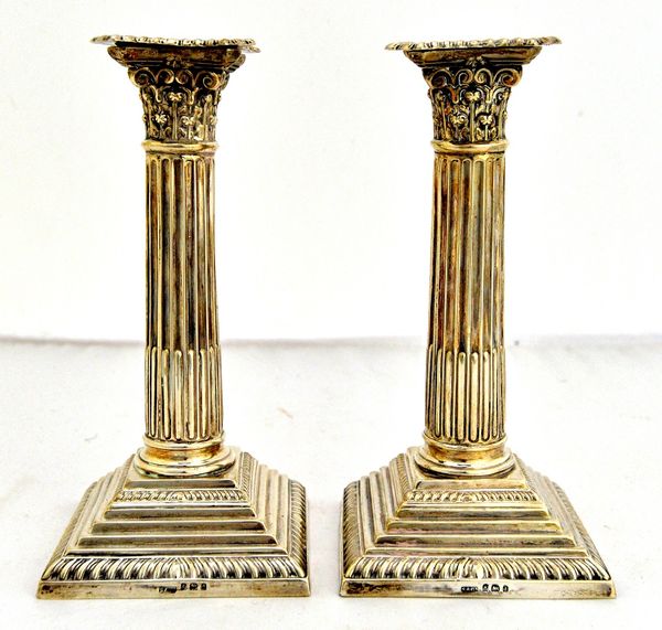 A pair of silver candlesticks, each formed as a Corinthian column, raised on a stepped square base, (loaded), Birmingham 1903, height 18cm.  Illustrat