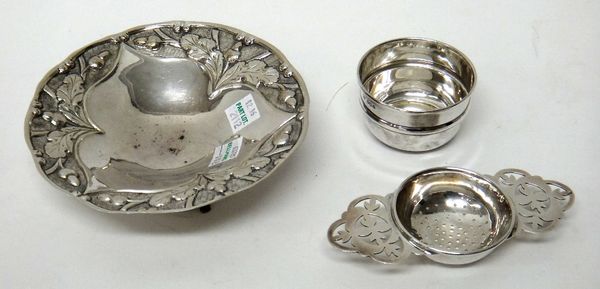 A silver twin handled tea strainer, with a silver bowl, Sheffield 1962 and a Greek circular dish, the border decorated with oak leaves and acorns and