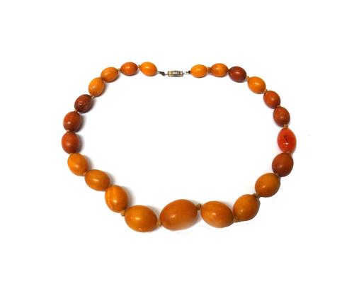 A single row necklace of graduated vary coloured butterscotch coloured oval amber beads, (the necklace includes one agate bead), combined gross weight