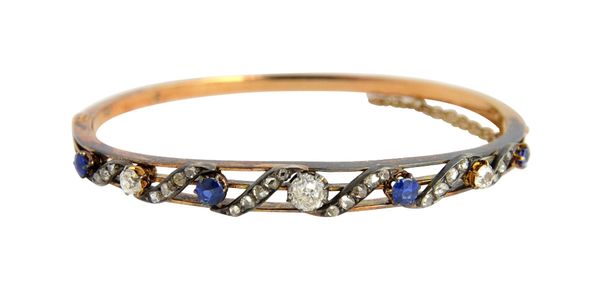 A Victorian gold and silver set, diamond and sapphire oval hinged bangle, the front in a scrolling design, mounted with three principal cushion shaped