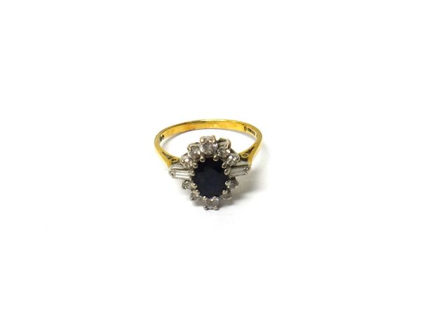 An 18ct gold ring, claw set with an oval cut sapphire, in a surround of circular cut and baguette diamonds, ring size K and a half, with a case.