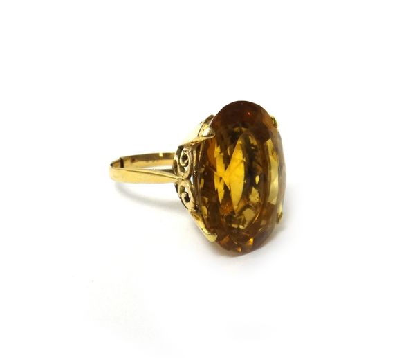 A gold ring, claw set with an oval cut citrine, ring size P (please note sprung clip to shank).