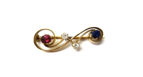 A gold, diamond, ruby and sapphire set brooch, in a scrolling design, the centre claw set with two cushion shaped diamonds and further set with a sing