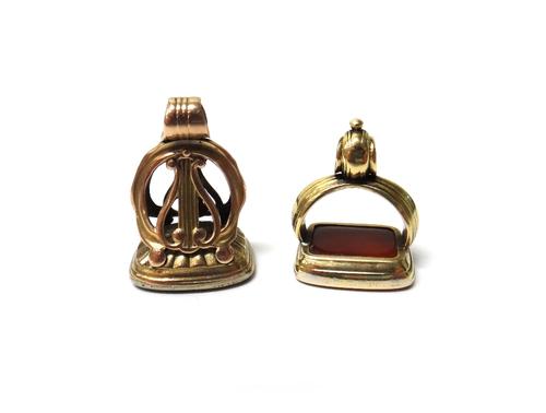 A Victorian cornelian pendant fob seal, engraved with a motto 'Vide Audi Tace', the mount with a lyre motif and another Victorian cornelain pendant fo