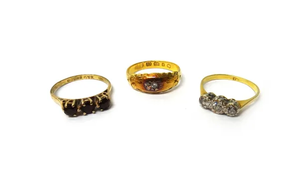 A gold and diamond three stone ring, mounted with a row of cushion shaped diamonds, a gold and diamond single stone ring and a 9ct gold and garnet thr