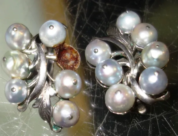 A pair of grey tinted cultured pearl set earclips, each in a fruiting design, mounted with seven grey tinted cultured pearls.  CAB