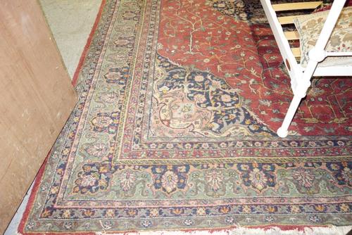 A Tabriz carpet, the claret red field with central blue and white Coptic cross design medallion within similar spandrels and green floral main border,
