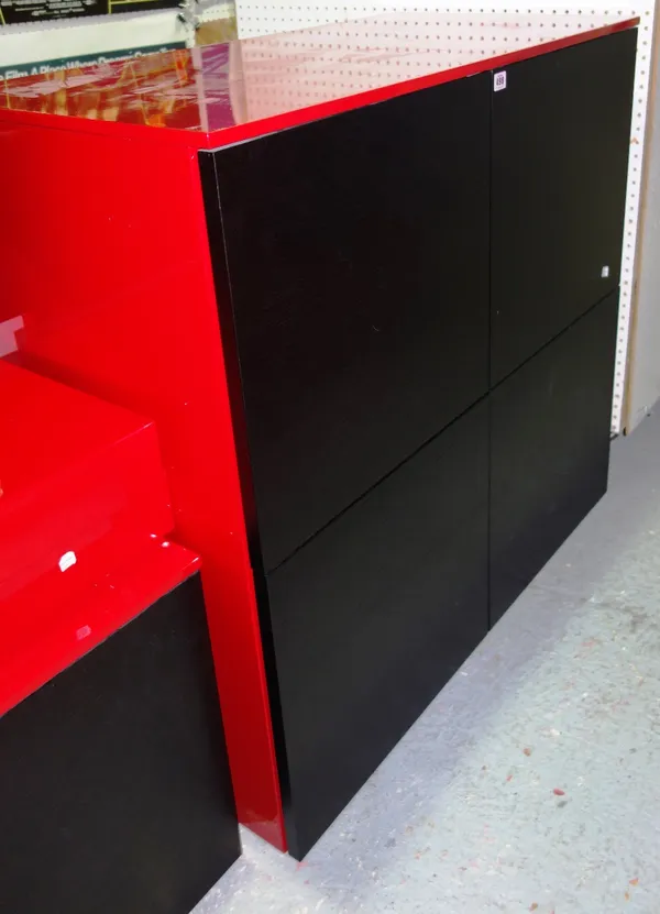 A 20th century black and red lacquered four door wall cabinet together with a pair of red shelves. (3)  GAL