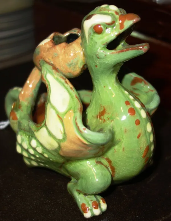 A C.H. Brannam pottery griffin candlestick, dated 1893, modelled with tail looped to form the handle, glazed in green, brown and cream. incised 'C.H.