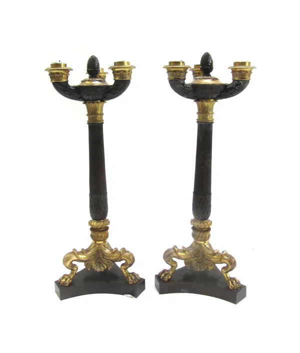 A pair of patinated and gilt bronze three branch candelabra, 19th century, with fluted tapering column and lion paw feet, on a triform plinth, 43cm hi