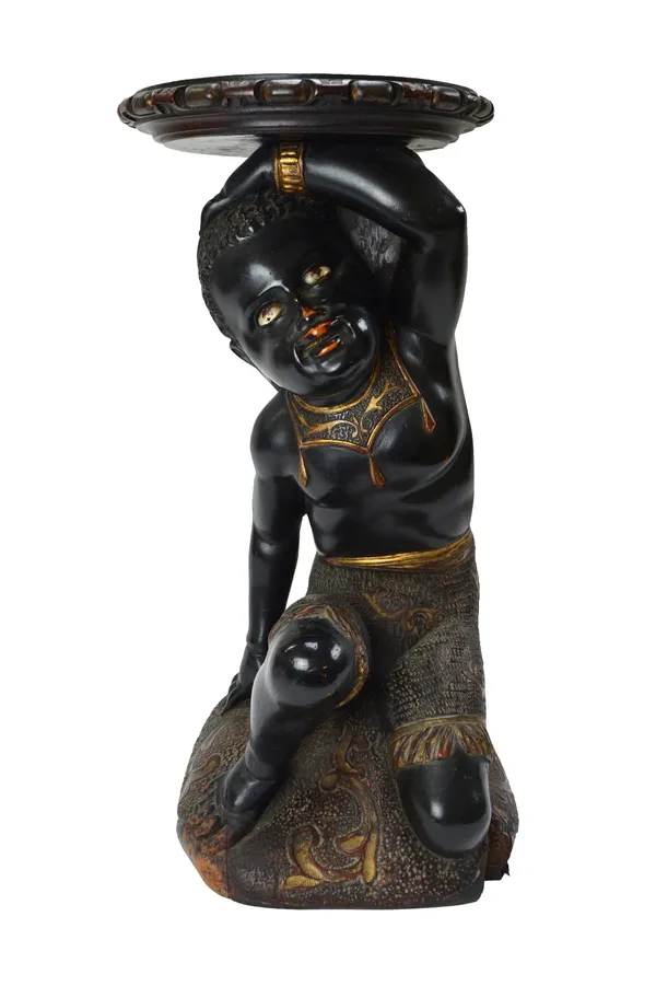 A Venetian polychrome and gilt Blackamoor stand, 19th century, with inset hardstone eyes, modelled kneeling atop a cushion base, 56cm high.  Illustrat