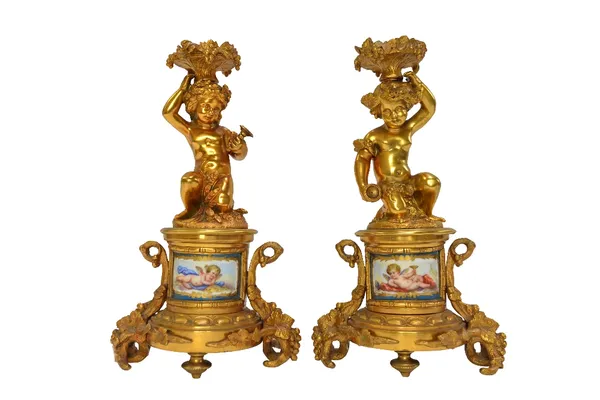 A pair of French ormolu figural candlesticks, circa 1880, each modelled and cast with Bacchanalian putti figures atop a circular base, inset with Sevr