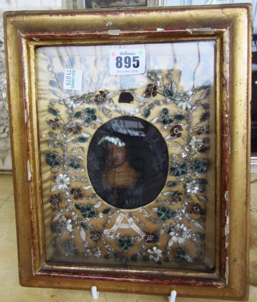 An oval portrait of a nun, early 19th century, with a wide seashell and silvered thread foliate border, framed and glazed (19cm x 15cm), an unusual Co