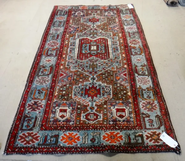 A Kurdish rug, the brown field with a bold   indigo medallion, an indigo rosette border, 200cm x 127cm.  I5