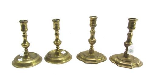 A pair of early Queen Anne brass baluster candlesticks with lozenge stepped bases, and a pair of early Queen Anne brass baluster candlesticks with cir
