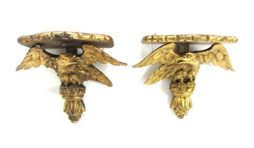 A pair of giltwood wall brackets, late 19th/early 20th century, each shaped shelf over an eagle and fruiting finial, 32cm high (2).