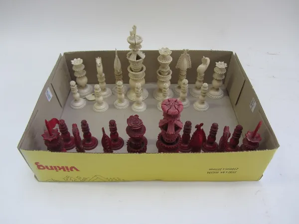 A 19th century Indian ivory chess set of ornately cast foliate form, with natural opposing red stained ivory pieces, the king 14.5cm high.