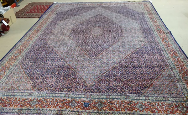 A Senneh carpet, Persian, the field with decreasing diamonds in dark and light indigo, all over herate design, a madder palmette border, 390cm x 296cm