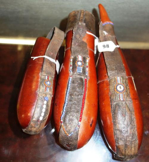 An African vessel, early 20th century, the body formed from a large nut, the leather lid and strap with coloured beadwork decoration (30cm) and two ot