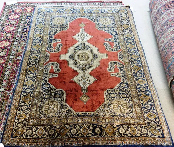 A Ghom silk rug, Persian, the plain madder field with an extended ivory medallion, matching spandrels, a black palmette and vine border, 152cm x 106cm