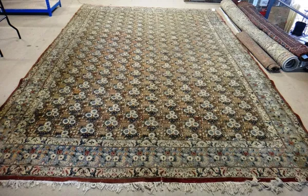 A Khorrasan carpet, Persian, with repeating triple flowerhead design, on an aubergine field, a floral indigo border, 394cm x 290cm.
