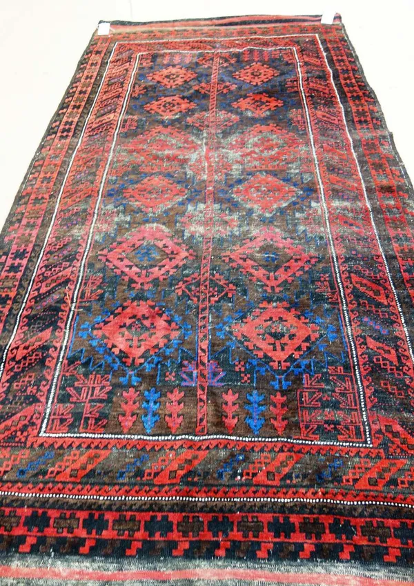 A Beluchistan carpet, the brown field with a stylised tree bearing pairs of madder rosettes, a banded border, 292cm x 148cm.