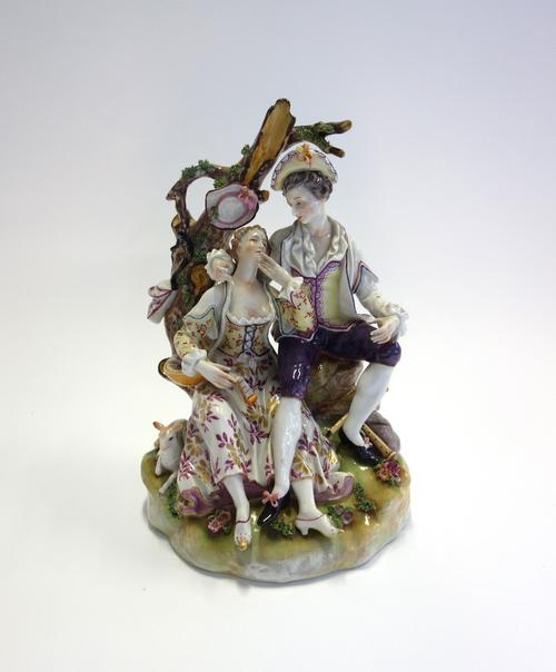 A Volkstedt porcelain figure group, late 19th century, modelled with gallant and companion under an arbour on a naturalistic base, blue painted mark t