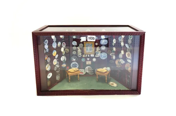 A miniature interior scene, mid 20th century, modelled as a panelled fireplace and glass shelves displaying various porcelain plates and similar items