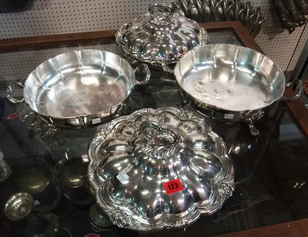 A pair of silver plated twin handled entree dishes, of shaped circular form, raised on four bold acanthus decorated feet.